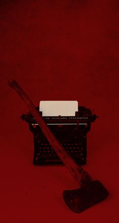 an old - fashioned typewriter with a wooden handle on a red background that is almost empty