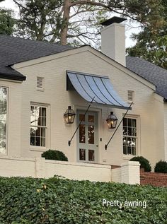 a white house with a blue awning on the front door and side entry way