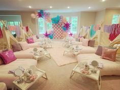 a living room filled with lots of white furniture and pink pillows on top of it