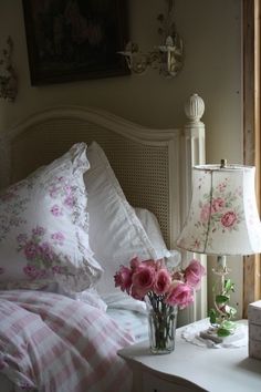 a white bed topped with pillows and pink flowers