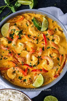 a bowl filled with shrimp and rice next to limes