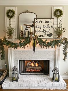 a fireplace decorated for christmas with greenery and candles on the mantel above it is a sign that says start each day with a thoughtful heart