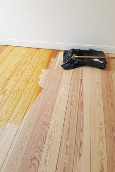 a pair of black gloves sitting on top of a wooden floor next to a wall