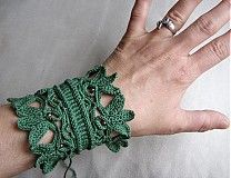 a woman's hand wearing a green crocheted bracelet with leaves on it