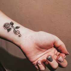 a woman's hand with a rose tattoo on the left side of her arm