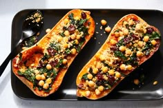 two stuffed sweet potatoes with chickpeas and spinach on a black serving tray