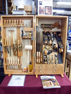 an open wooden box with many different tools in it on a purple table cloth next to a magazine