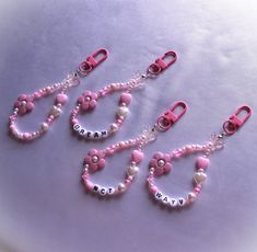 three pink and white beaded necklaces with name charms attached to them on a purple surface