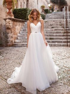 a woman in a white wedding dress standing on some steps