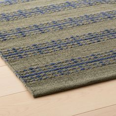 a gray rug with blue and grey designs on it, sitting on a wooden floor