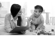 a woman sitting next to a child on the floor with blocks in front of her