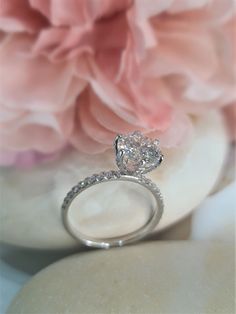 a diamond ring sitting on top of a white plate next to pink flowers and peonies