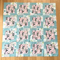 a pink and blue patchwork quilt on a wooden floor