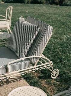 two chairs and a table sitting on top of a grass covered field next to each other