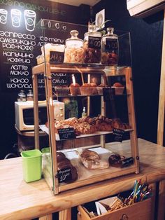 a display case filled with lots of pastries on top of a wooden table next to a chalkboard