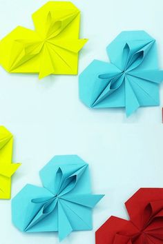 three origami flowers on a white surface with one red and one blue folded in half