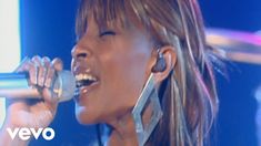 a woman singing into a microphone with her eyes closed and mouth wide open on stage