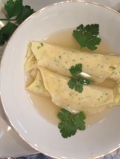 two ravioli with parsley in a white bowl on a blue and white table cloth