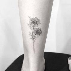 a black and white photo of a woman's leg with sunflowers on it