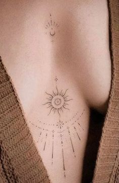 the back of a woman's breast with sun and moon tattoos on it