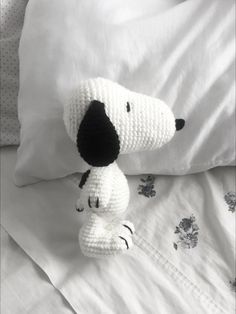 a crocheted dog sitting on top of a bed next to white sheets and pillows