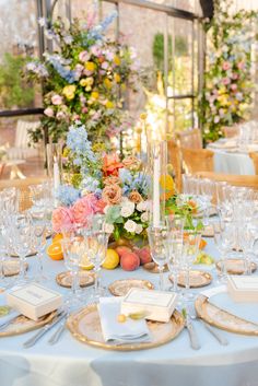 the table is set with many wine glasses and place settings for guests to sit at