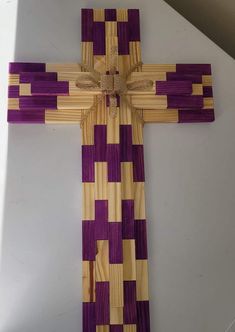 a cross made out of wood with purple and yellow squares on it's sides