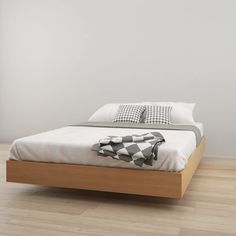 a bed sitting on top of a hard wood floor next to a white painted wall