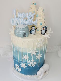 there is a cake decorated with penguins and snowflakes on the top, along with an iceman figurine