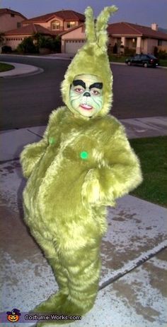 a person in a green bunny costume standing on the sidewalk with their hands behind his back