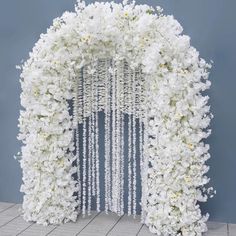 white flowers are hanging from the side of a floral arch