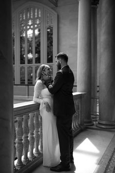 a man and woman standing next to each other in front of some pillars with columns