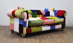 a multicolored couch sitting on top of a hard wood floor