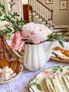 a table topped with plates filled with food and flowers on top of a table cloth