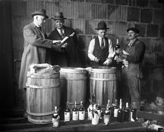 three men are standing around some barrels with bottles