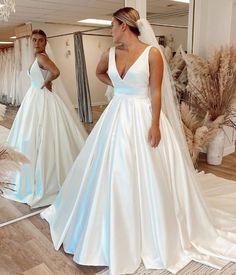 a woman standing in front of a mirror wearing a white wedding dress and looking at her reflection