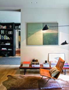 a living room filled with furniture and a painting on the wall next to a coffee table