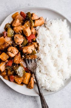 a white plate topped with rice and chicken next to a fork on top of it