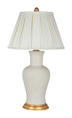 a white table lamp with a gold base and shade on the top, against a white background