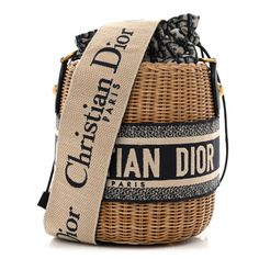 This is an authentic CHRISTIAN DIOR Wicker Oblique Drawstring Bucket Bag in Blue. This small bucket-style bag is crafted of wicker with Dior monogram canvas and blue leather and embroidered Christian Dior logo trim. The bag features an adjustble beige and blue canvas shoulder strap and aged gold hardware. The center canvas interior opens with a cinch cord to a patch pocket. Designer Monogram Canvas Bucket Bag, Luxury Woven Leather Straw Bucket Bag, Luxury Straw Bucket Bag With Woven Leather, Luxury Beige Basket Bucket Bag, Designer Woven Leather Bucket Straw Bag, Designer Woven Leather Straw Bucket Bag, Designer Summer Bucket Bag, Designer Natural Straw Bucket Bag, Designer Natural Bucket Straw Bag