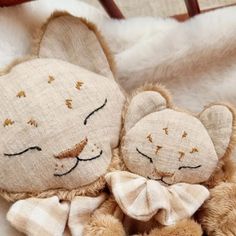 two brown teddy bears laying on top of a white blanket