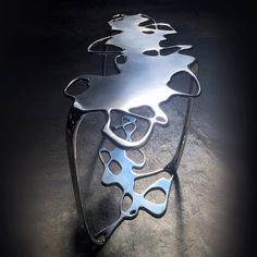 a metal table that is sitting in the middle of some concrete flooring with an artistic design on it