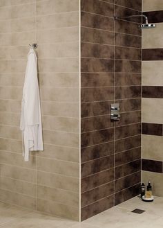 a bathroom with brown and white tiles on the walls, shower head and hand rail