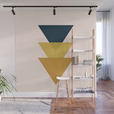 a wall mural with geometric shapes on it in a living room, next to a chair and bookshelf