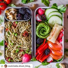 two trays filled with different types of vegetables and pasta, one containing cucumber, the other topped with blackberries