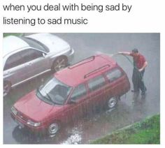 a man standing next to a red car in the rain