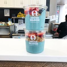 two plastic cups filled with yogurt and strawberries on top of a counter