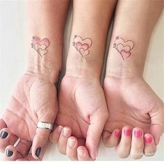 two girls with matching tattoos on their arms holding hands in the shape of three hearts