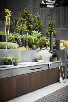 an outdoor kitchen with potted plants on the counter