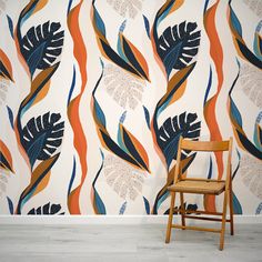 a wooden chair sitting in front of a wall with an orange and blue pattern on it